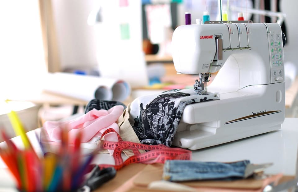 Professional sewing machine with colorful fabrics and sewing supplies in a bright creative workspace